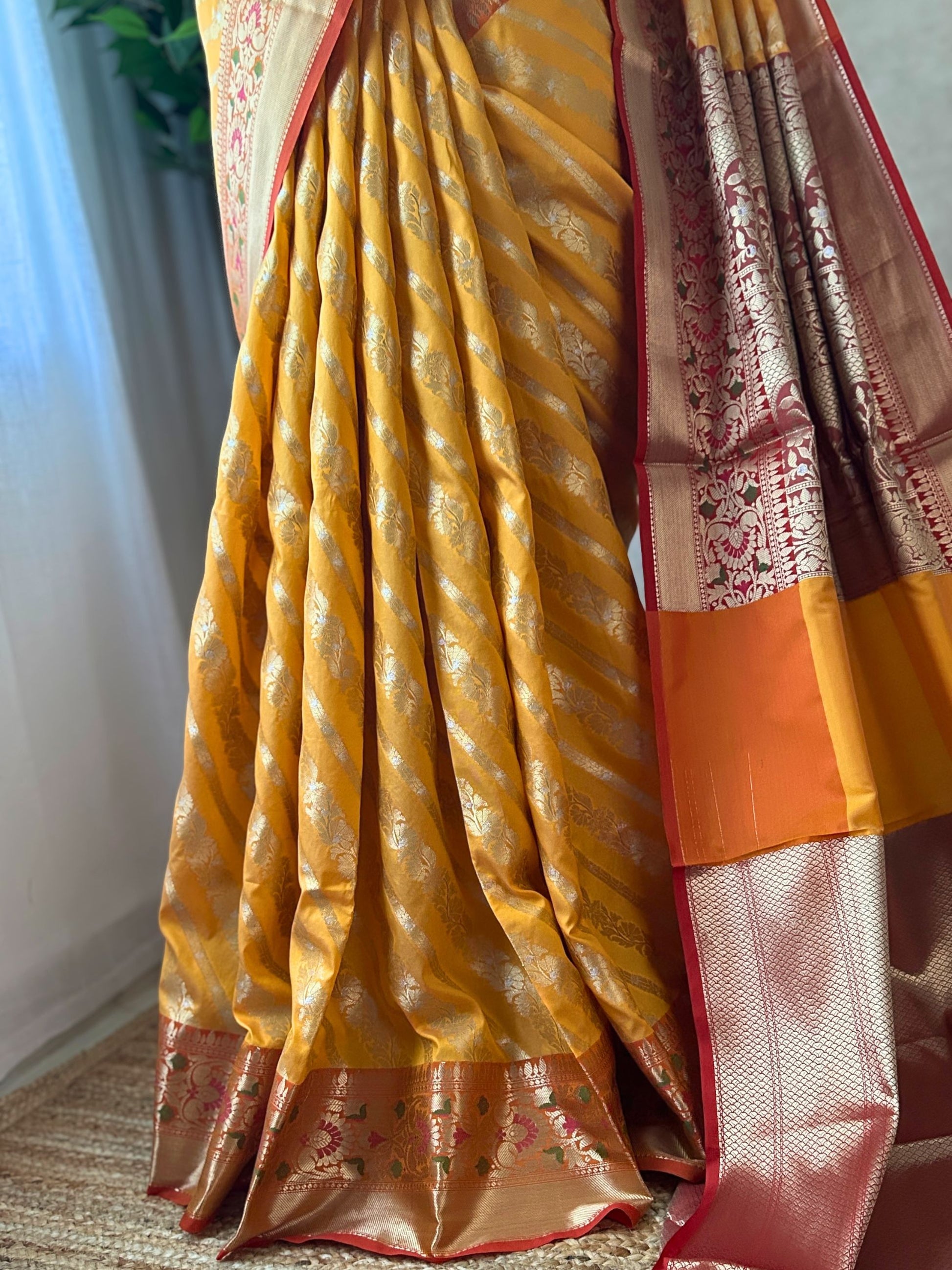 Silver zari jal detailing on orange yellow Banarasi saree