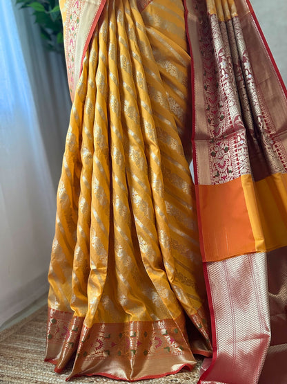 Silver zari jal detailing on orange yellow Banarasi saree
